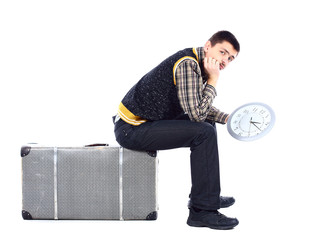 Young man waiting at airport, holding big clock