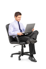 Young smiling businessman sitting in office chair and working on