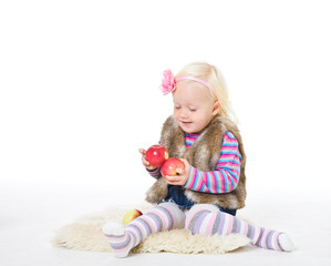 Little blond girl holding a red apple sitting on the floor