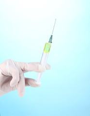 Syringe in hand on blue background