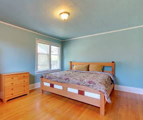 Blue bedroom with oak floor and large bed.