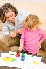 Little girl with grandmother play paint handprints