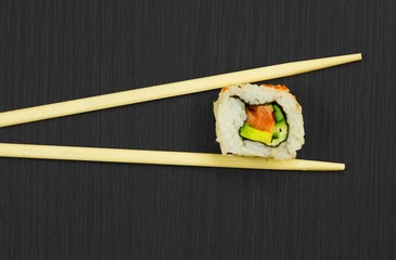 Sushi and sticks isolated on black wooden board