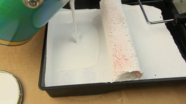Pouring paint in roller tray then rolling a paint roller