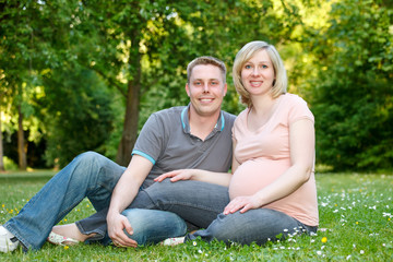 Naklejka na ściany i meble Pregnant couple in the park