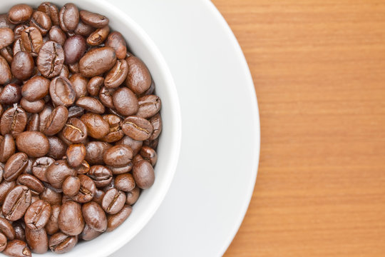 Close up image of coffee beans in white cup and saucer