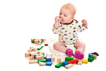 Infant girl playing with building bricks isolated on white