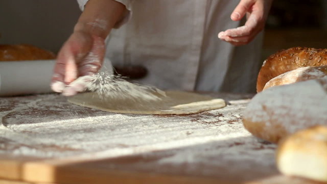 Baker hand throwing flour on the table and preparing pizza dough