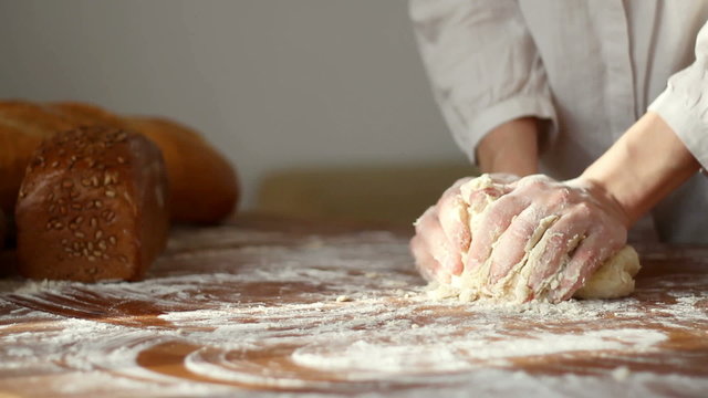 Female hands kneading dough in flour on table