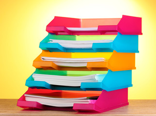 bright paper trays on wooden table on yellow background