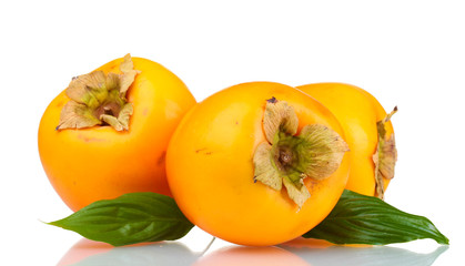 Three appetizing persimmons with green leaves isolated on white