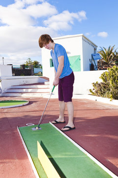 Boy Playing Mini Golf In The Course