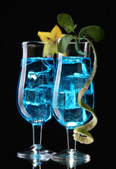 Blue cocktail in glasses on black background