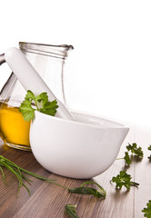 Mortar for herbs with olive oil on wooden background