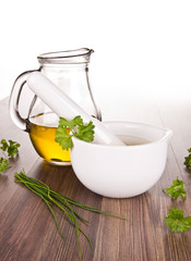 Mortar for herbs with olive oil on wooden background