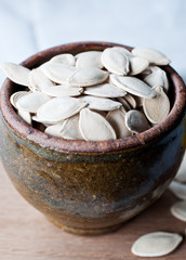 Ceramic bowl full of pumpkin seeds on kitchen table background