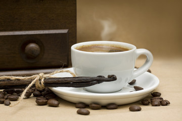 Coffee, beans and vanilla on brown background