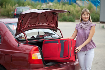 girl puts the suitcase in  car