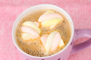 Cup of cappucino with marshmallows on pink background