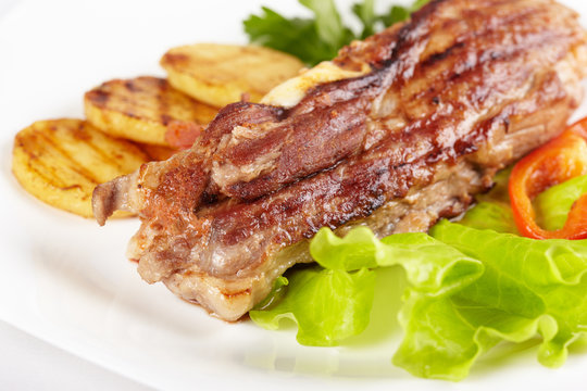 Grilled meat with vegetables on white plate