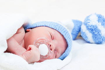 newborn baby  sleeps in a knitted striped hat