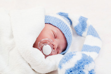 newborn baby  sleeps in a knitted striped hat