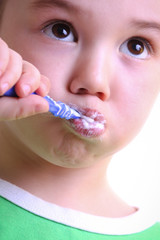 an adorable little boy brushing his teeth on white background