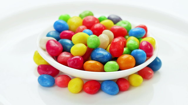 Multicolor bonbon sweets rotating on white plate, loop ready