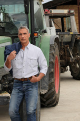 Obraz premium Farmer stood by tractor