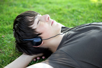 Teenager lying on grass listening to music