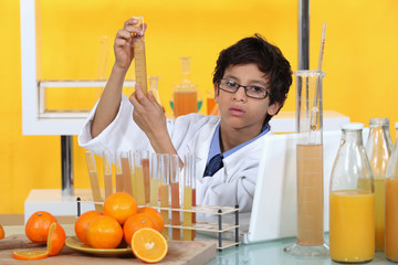 Little boy conducting experiment on orange juice