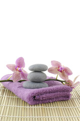 pink towel and stones and orchid on bamboo mat