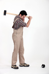 a carpenter breaking piggy bank with hammer