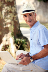 Middle-aged man sat in park with laptop