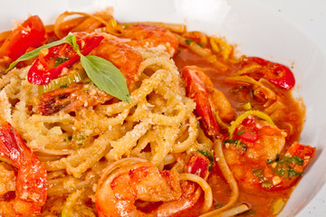 A plate of linguini with sauteed shrimp, tomato, chili  and oliv