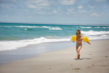 Fototapeta na wymiar young boy running by sand beach