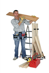 A handyman carrying a wooden plank