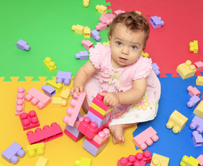 Adorable baby girl plays with multicolored blocks toy