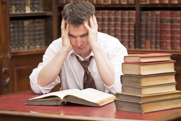 Stressed young student with a pile of books to read