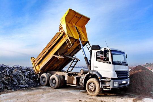 Dump truck is dumping gravel on an excavation site