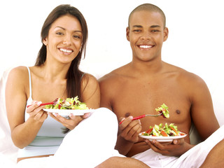 Pareja latina comiendo ensalada de vegetales.