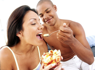 Pareja hispana compartiendo y comiendo ensalada de frutas.