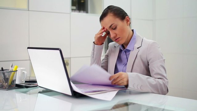 Young businesswoman overwhelmed by too much paperwork in office