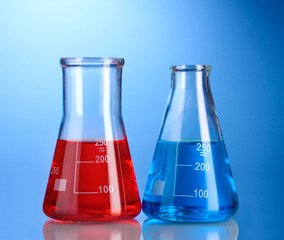 Two flasks with red and blue liquid with reflection