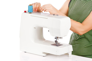 Woman is sewing on the sewing machine on a white background