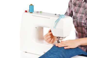 Woman is sewing on the sewing machine on a white background