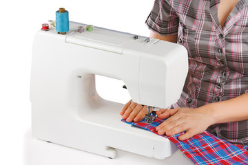 Woman is sewing on the sewing machine on a white background