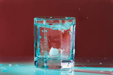 Glass of fresh ice water in a turquoise light