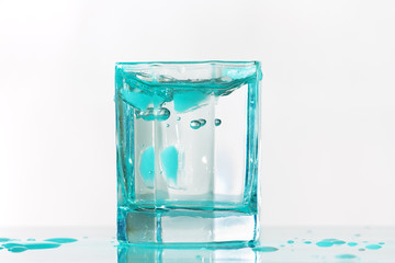 Glass of fresh ice water in a turquoise light