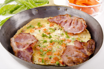omelette with carrot and bacon in a pan